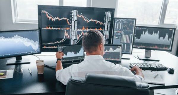 A day trader sits in front of a bunch of computer screens